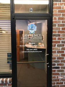 Close up photo of glass door entrance to Lawrence Family Dentistry office, red brick building, logo on door